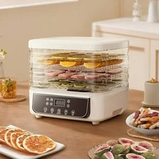 A countertop food dehydrator holding trays of sliced fruit.