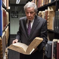 A person examining and collecting books in a library