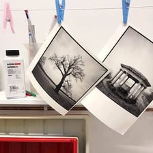 A photographer working under dim red light while developing photographic prints.