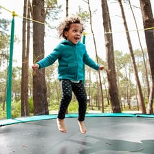 A child bouncing on a trampoline, illustrating its springy surface.