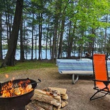 A campground with tents and a contained campfire