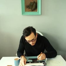 An author writing a manuscript at a desk.