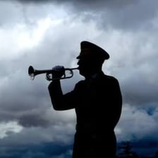 Military bugler sounding a morning wake-up call at dawn
