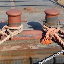 A heavy bollard on a dock with a ship’s mooring rope secured around it