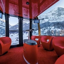 An enclosed gondola cabin traveling above a ski slope.