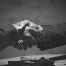 Two people shaking hands as one makes a promise
