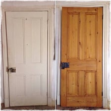 A person removing paint from a wooden door with a scraper.