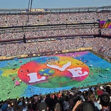A colorful inflatable beach ball being tossed above a stadium crowd.