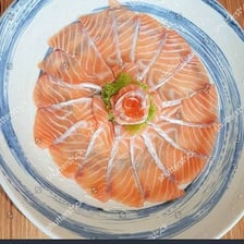 A plate of thinly sliced raw fish prepared as sashimi