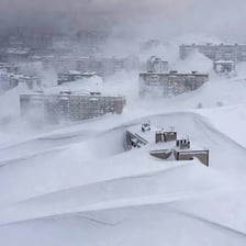 A snowy landscape being affected by intense snow and blowing wind.
