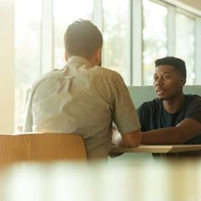 Two people engaged in a direct, serious conversation.