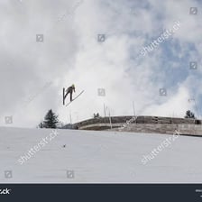 A snowy ski-jump ramp rising steeply above the landing hill.