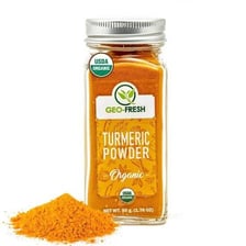 Fresh turmeric rhizomes beside a pile of yellow turmeric powder