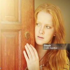 A person lingering uncertainly near a doorway.