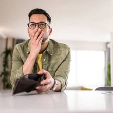A person looking at an empty wallet, representing financial difficulty.