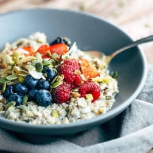 A bowl of muesli containing oats and pieces of fruit.