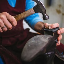A shoemaker repairing the heel of a shoe at a workbench