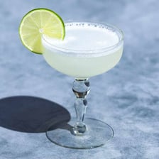 A pointed gimlet tool beside a gimlet cocktail