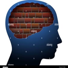 A person facing a brick wall used as a metaphor for a mental block