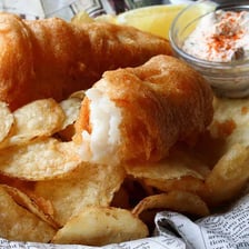 A piece of battered fish served with chips