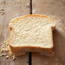 Sliced loaf of bread with crumbs scattered on a table