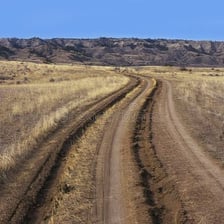 A deep furrow left by vehicle wheels on a dirt road