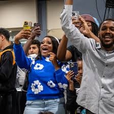 A crowd cheering in celebration with raised arms.