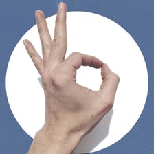 A person making an OK hand gesture with a neutral expression