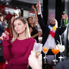 An unhappy person standing apart from people enjoying a party.