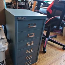 An office filing cabinet beside a hand using a nail file.