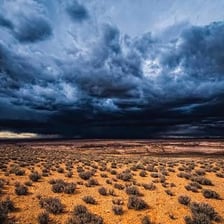 A dark storm cloud appearing large and threatening over a landscape.