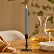 A taper candle producing a small, weak flame