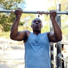 A person performing a pull-up on a horizontal exercise bar.