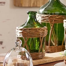 A large bulbous glass demijohn bottle with protective wicker covering.