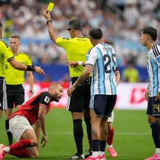 A football referee holding up a yellow card to a player