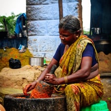 A cook using a pestle to grind ingredients in a mortar.