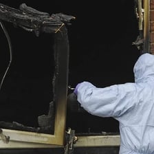 Fire-damaged building being examined after a suspected arson.