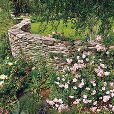 A stone wall surrounding and enclosing a garden.