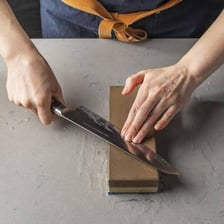 A person sharpening a knife on a whetstone