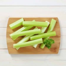 A fresh celery stalk on a cutting board.