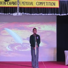 A person reciting a poem or speech on a stage.