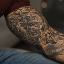 A close-up of an arm covered with tattoo designs.