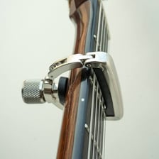 A clamp-style capo attached across the neck of an acoustic guitar.