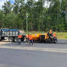 Workers laying asphalt on a parking lot.