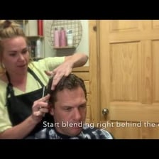 A barber making a small haircut adjustment with scissors.
