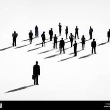 A person standing apart from a social group with a distant demeanor.