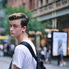 A teenage student walking on a college campus