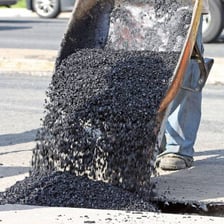 Dark paving material being applied to a road.