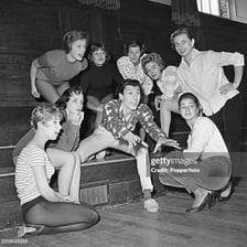 A group of actors posing together on a theater stage.