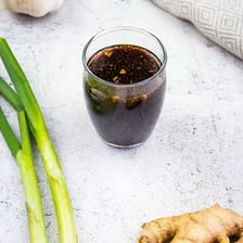 Fresh ginger root beside a bowl of teriyaki sauce